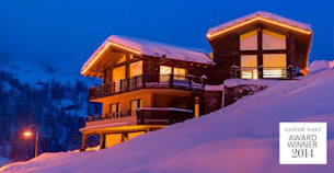 Les Anges luxury chalet illuminated at night by the soft glow of lights and set in a romantic blanket of Alpine snow.